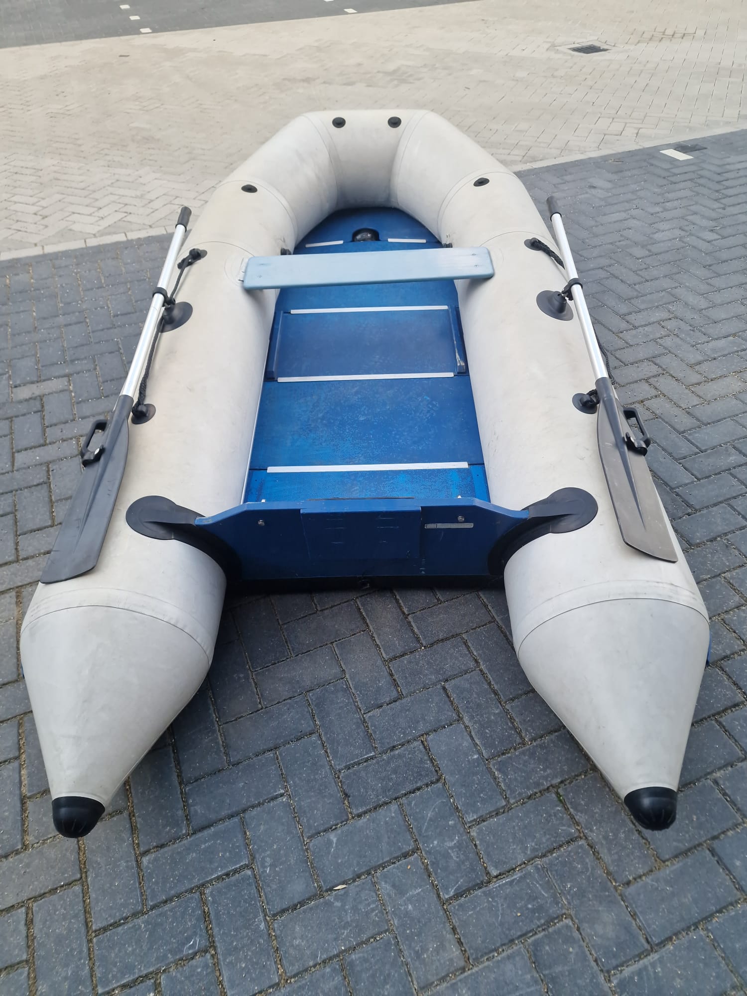 Grijze rubberboot met aluminium vlonder en riemen